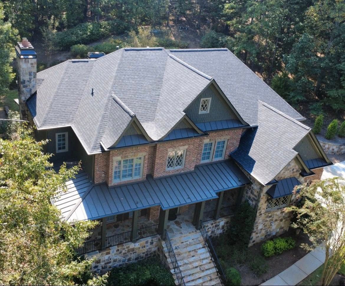 Multi-level house with dark grey roof and stone and brick facade.