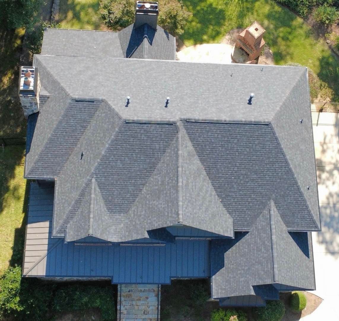 Overhead view of a house with a dark gray shingle roof and chimneys.