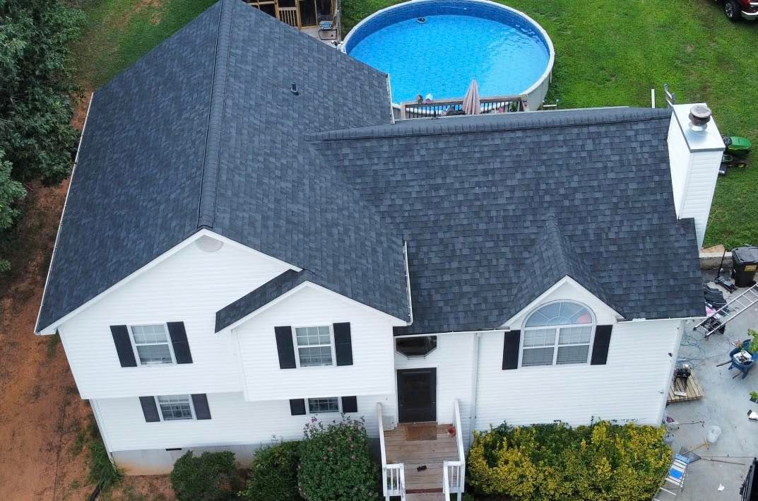 Overhead view of a white two-story house with a dark gray roof, backyard with a pool.