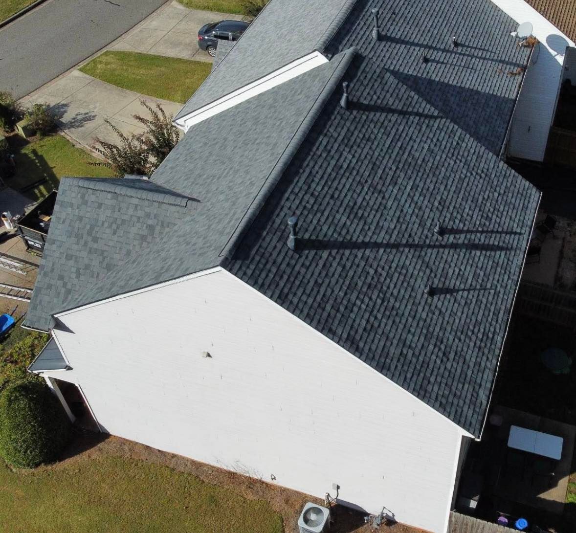 An aerial view of a house with a gray shingled roof and white exterior walls.