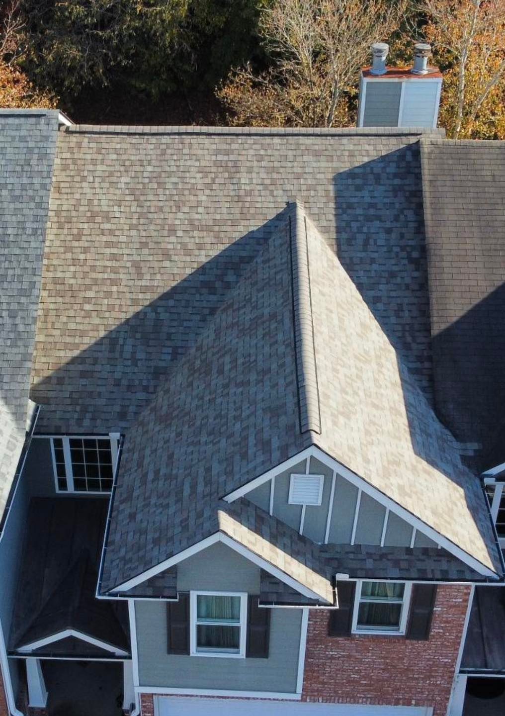 Overhead view of a house with a gray shingle roof, chimney, and brick exterior.