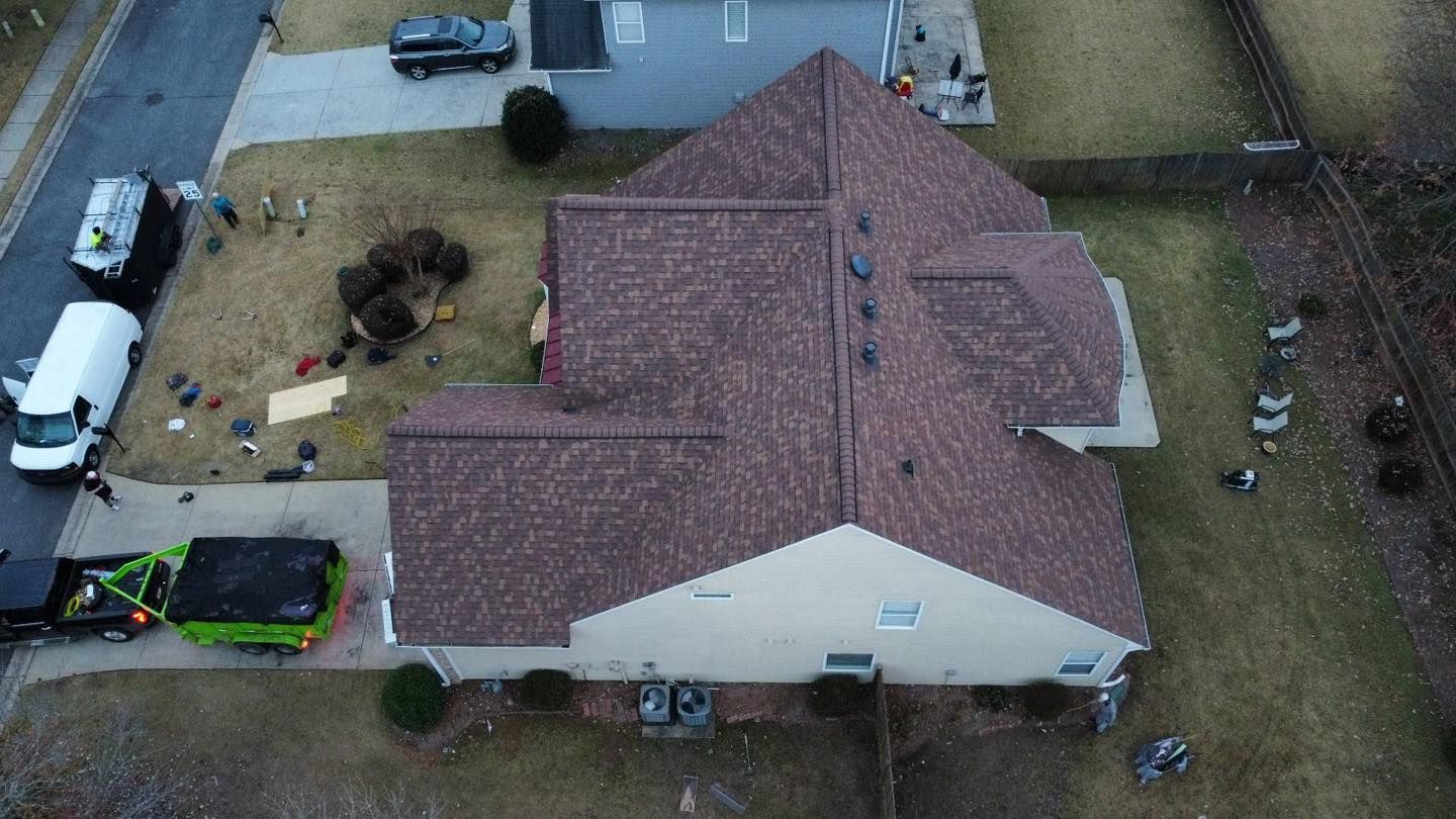 Overhead view of a house with a brown roof and a truck in the driveway with yard debris.