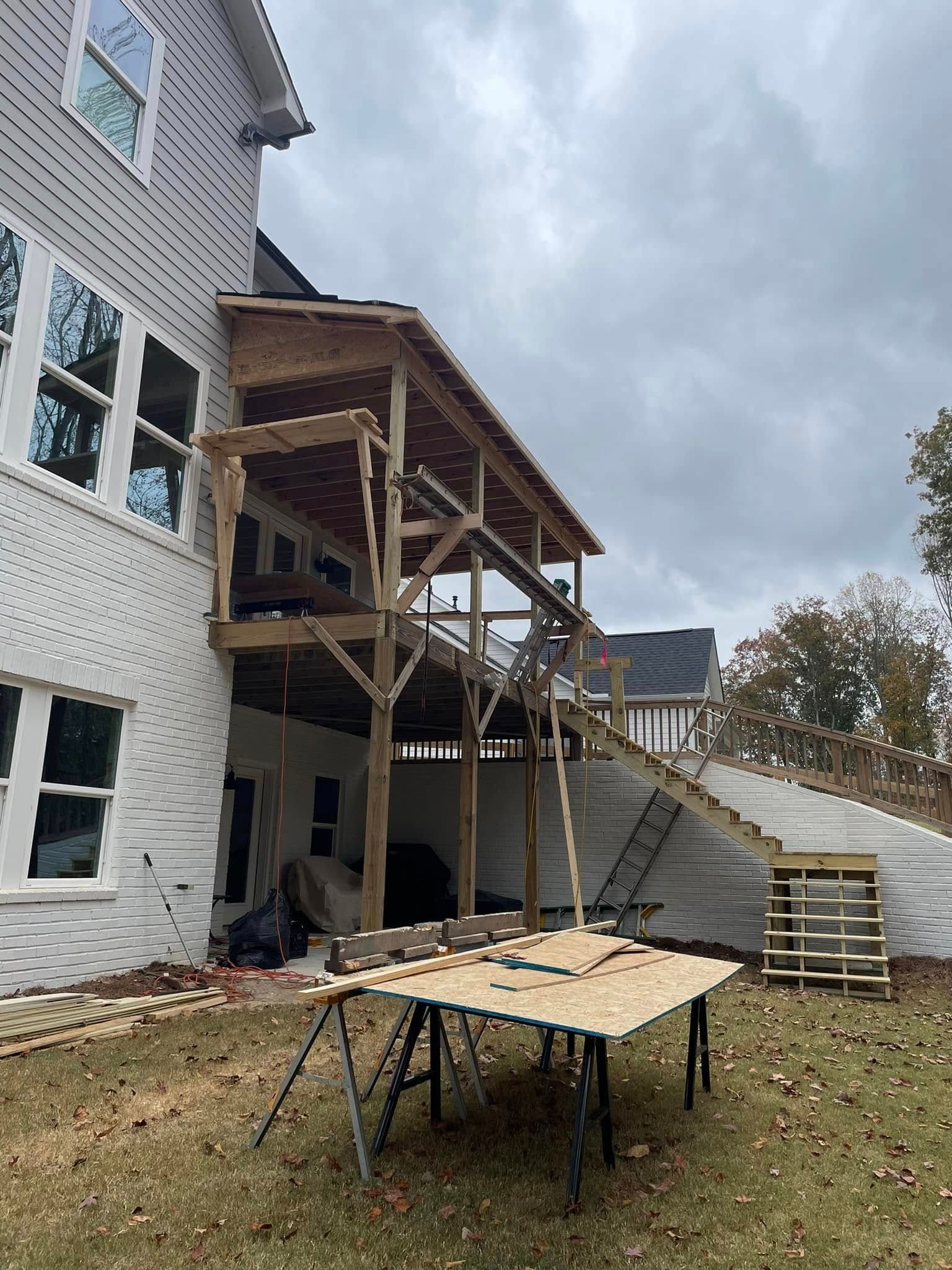 Deck construction; two-level wooden deck attached to a house with stairs. Overcast sky.