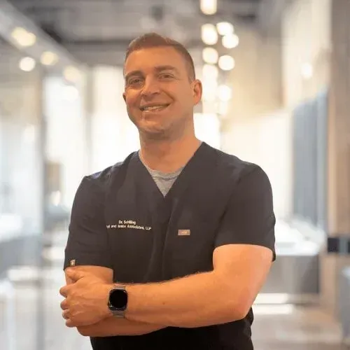A smiling doctor in a lab coat with a stethoscope around his neck.