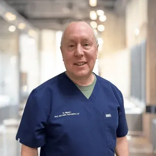 A smiling doctor in a lab coat with a stethoscope around his neck.