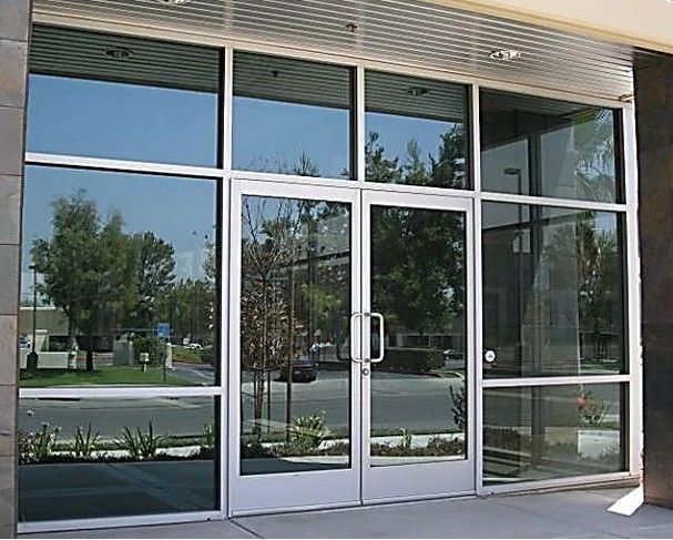 Glass storefront entrance with double doors and reflective windows under a covered awning