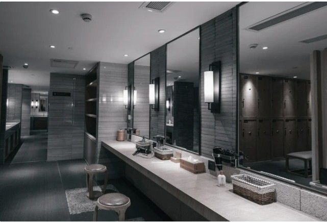 Modern bathroom with double vanity, large mirror, and soft wall sconces in gray tones