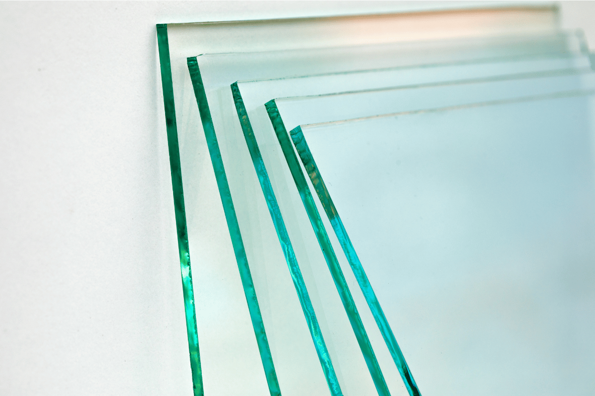 Stacked glass sheets with green-tinted edges on a white background