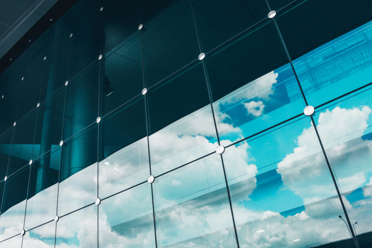 Glass building facade reflecting blue sky and clouds