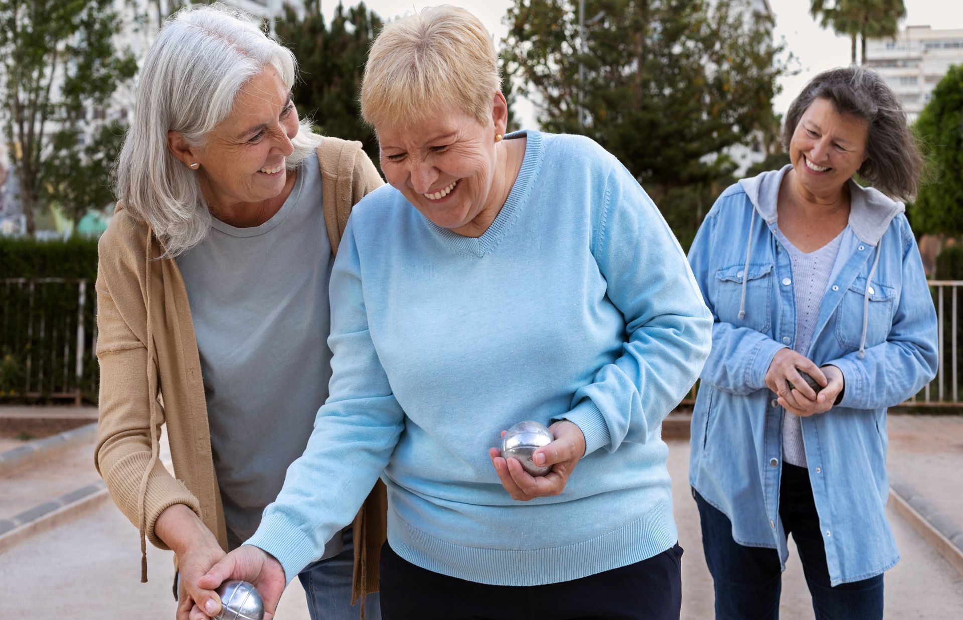 hogar gardenias Tres mujeres mayores juegan a la petanca en un parque.