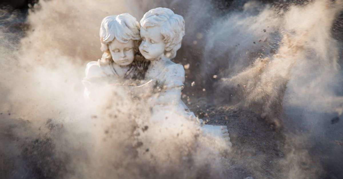 Beeld van twee cherubijnfiguren die elkaar omhelzen, te midden van een stofwolk.