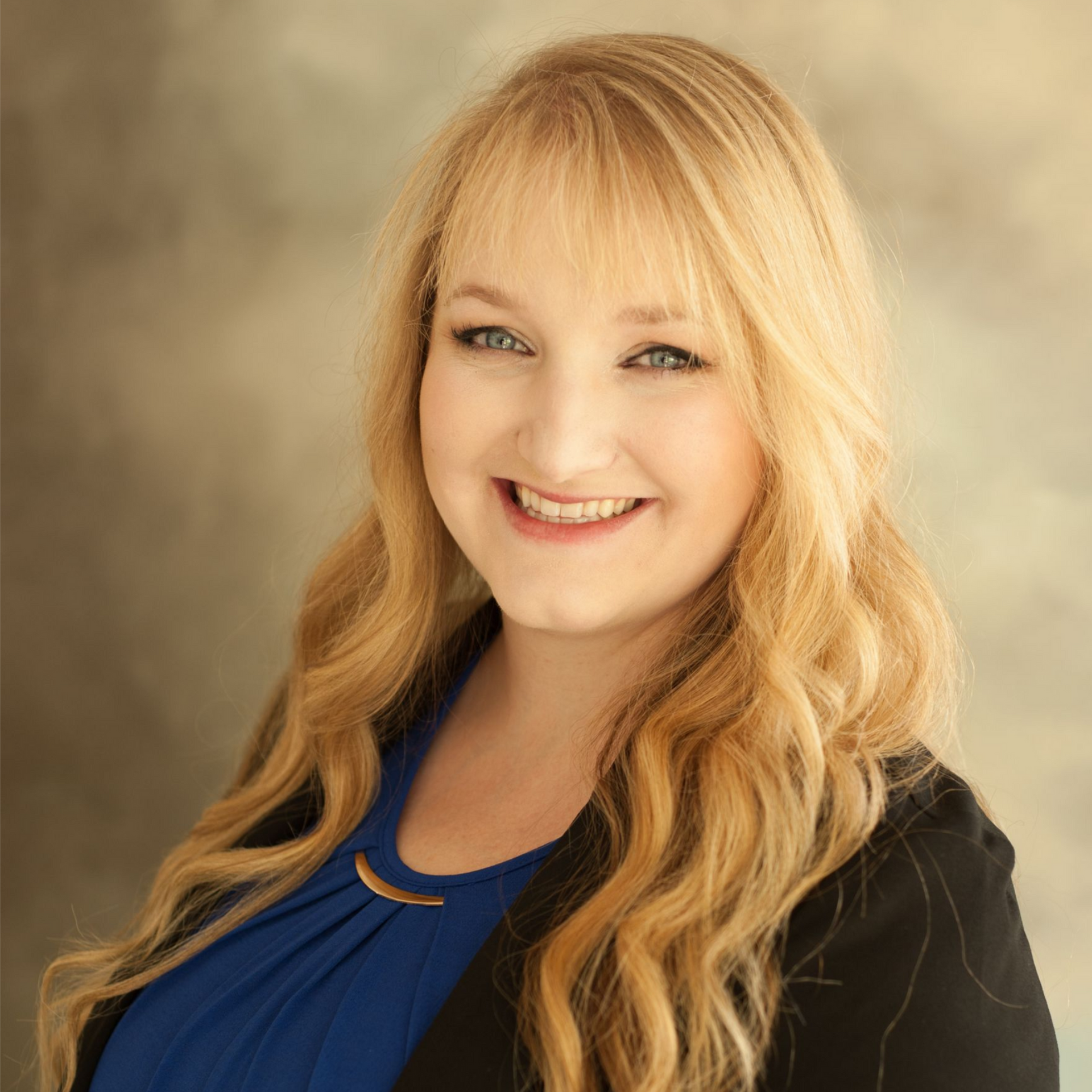 Woman with long blonde hair smiles, wearing a blue shirt and black blazer.