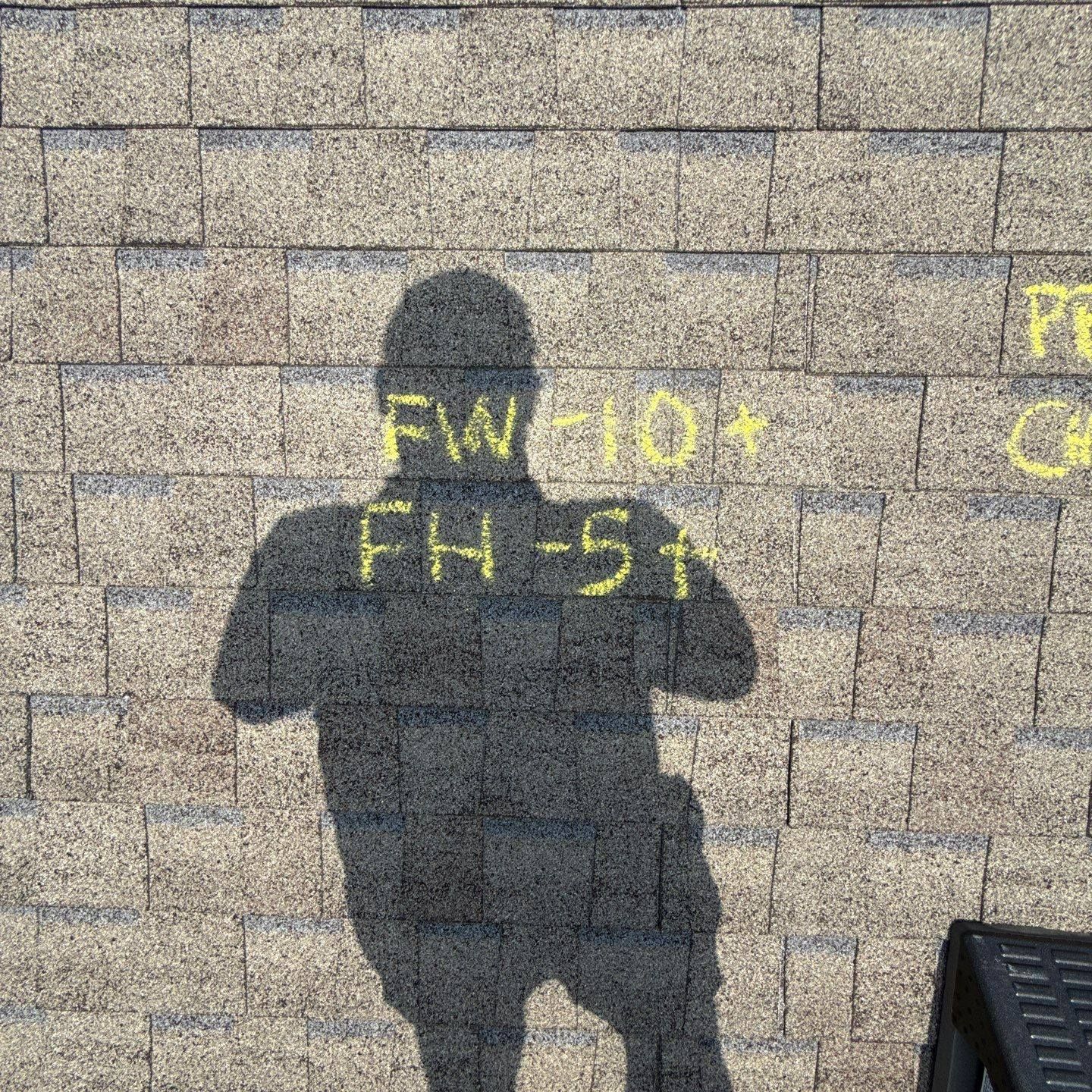 Shadow of a person on a textured roof; yellow markings