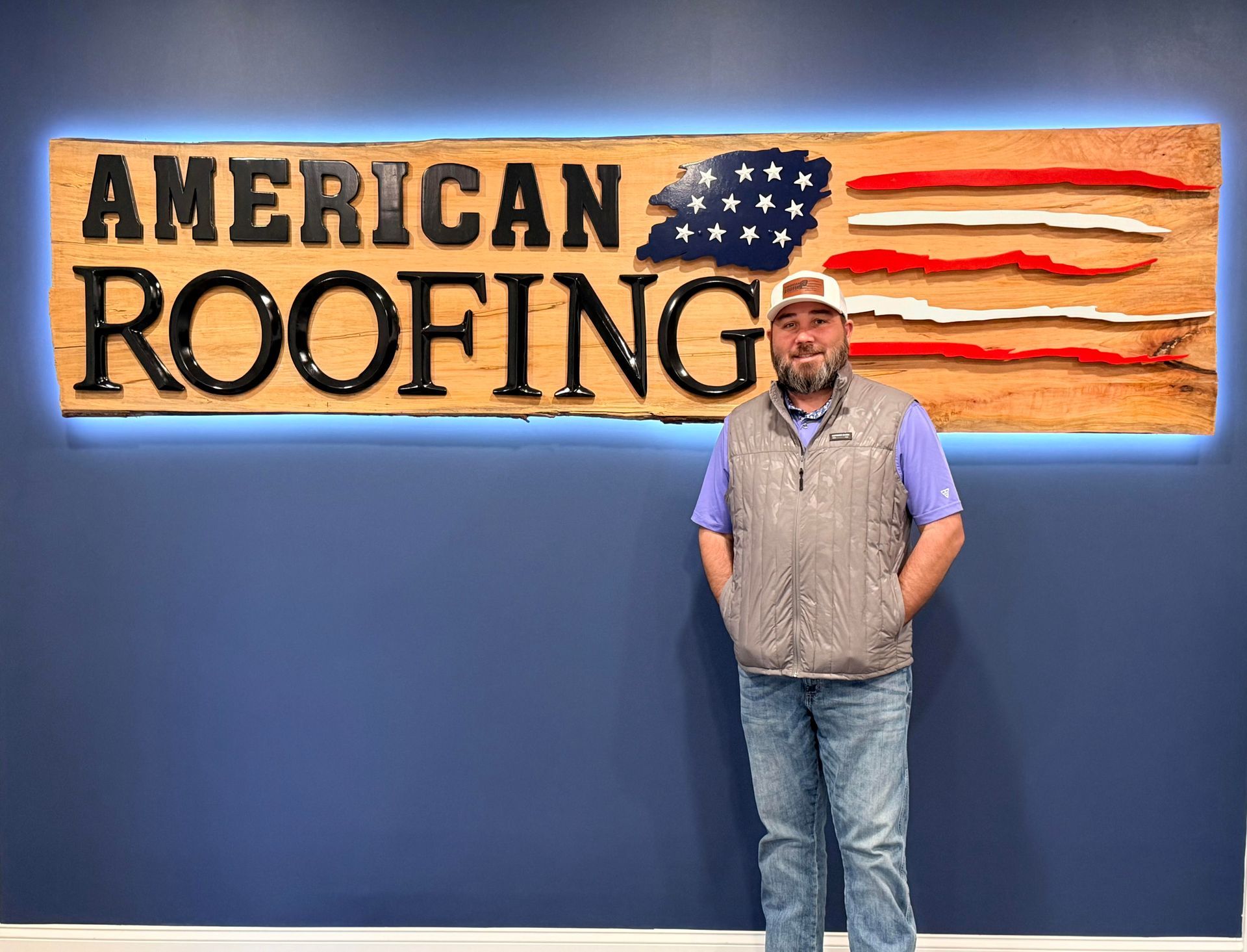 Brandon Clark owner and operator of American Roofing and Renovation standing beside the company sign