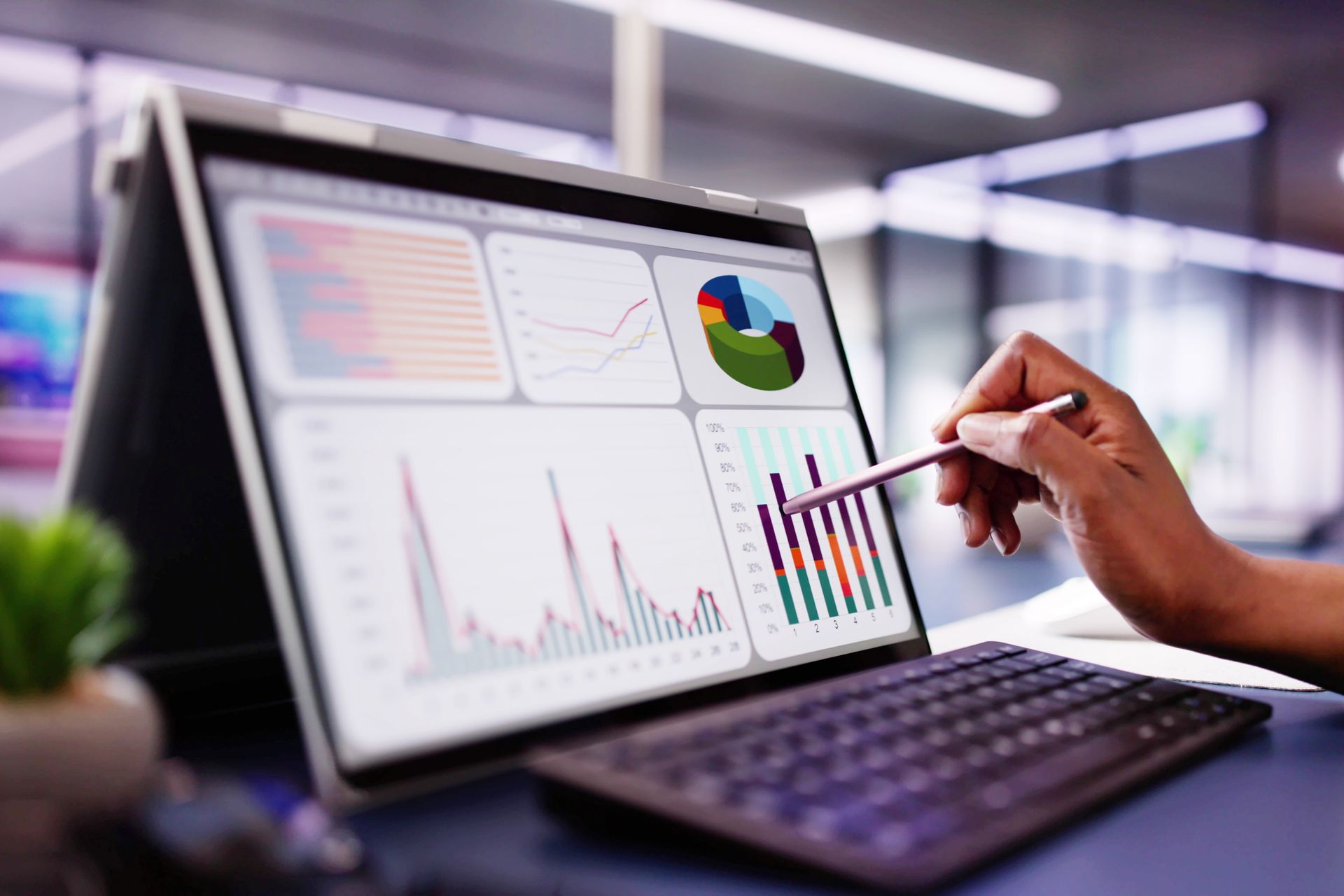 A person is pointing at a graph on a laptop computer.