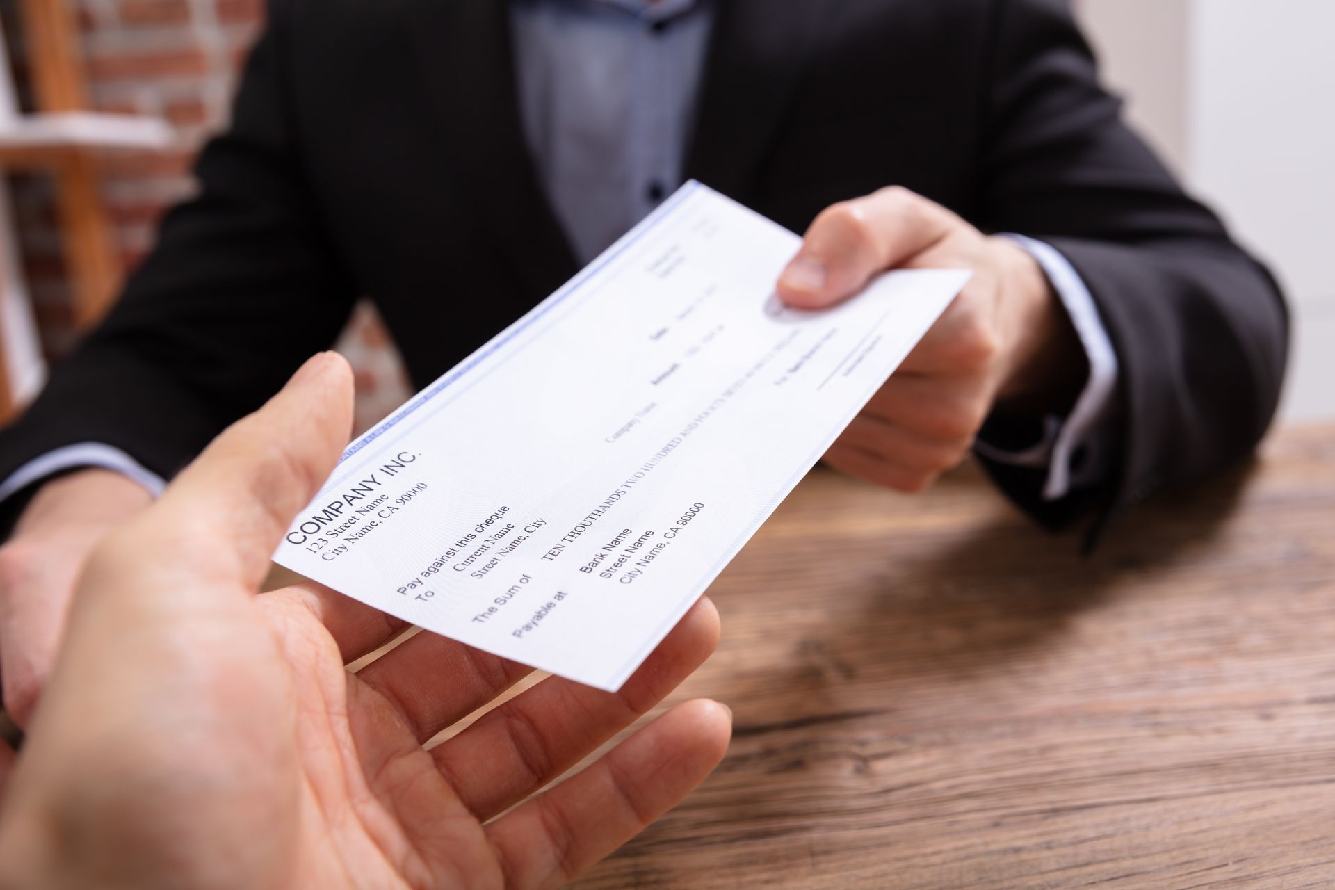 A man in a suit is handing a check to another man.