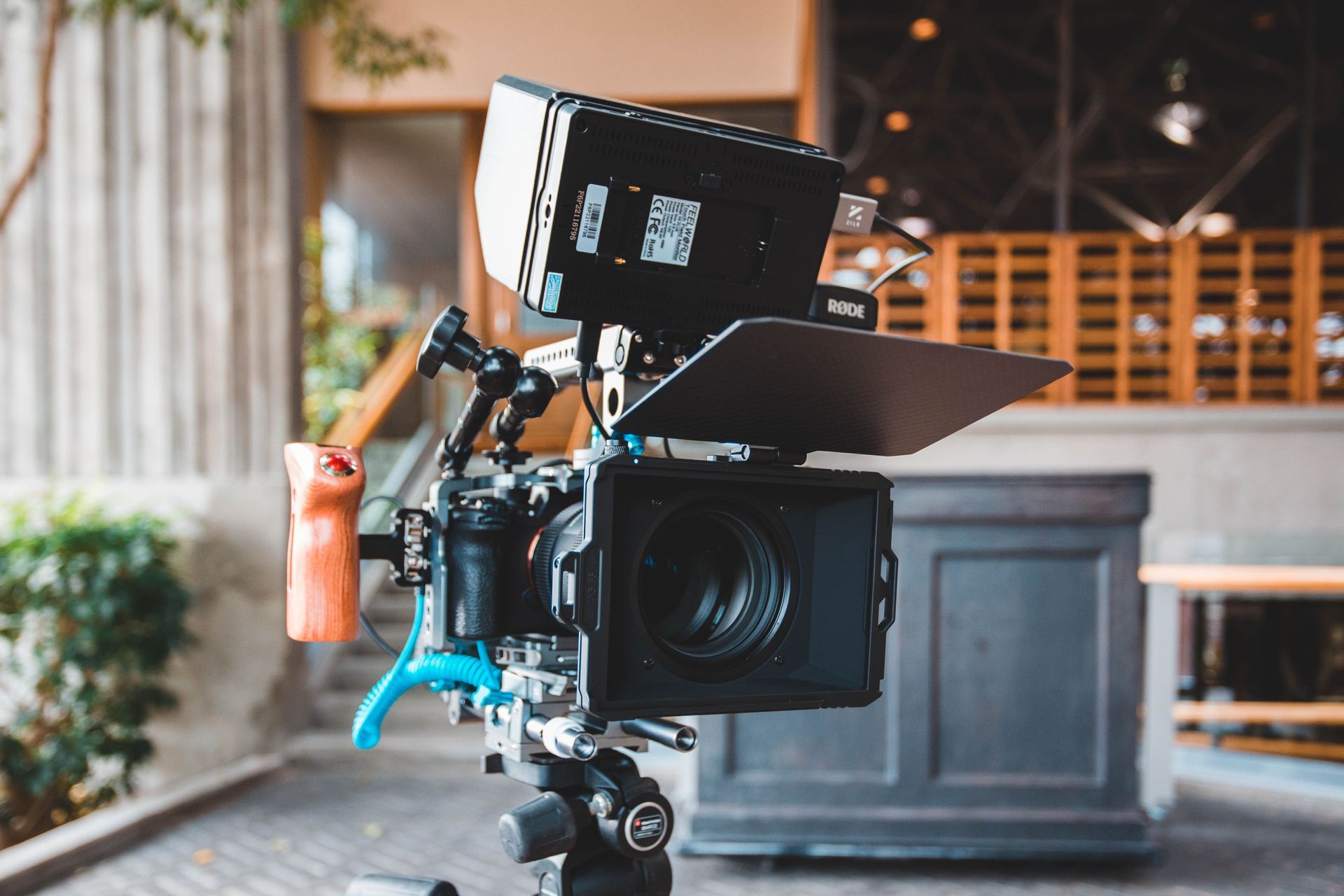 Professional video camera on a tripod with attached monitor and matte box in a studio setting