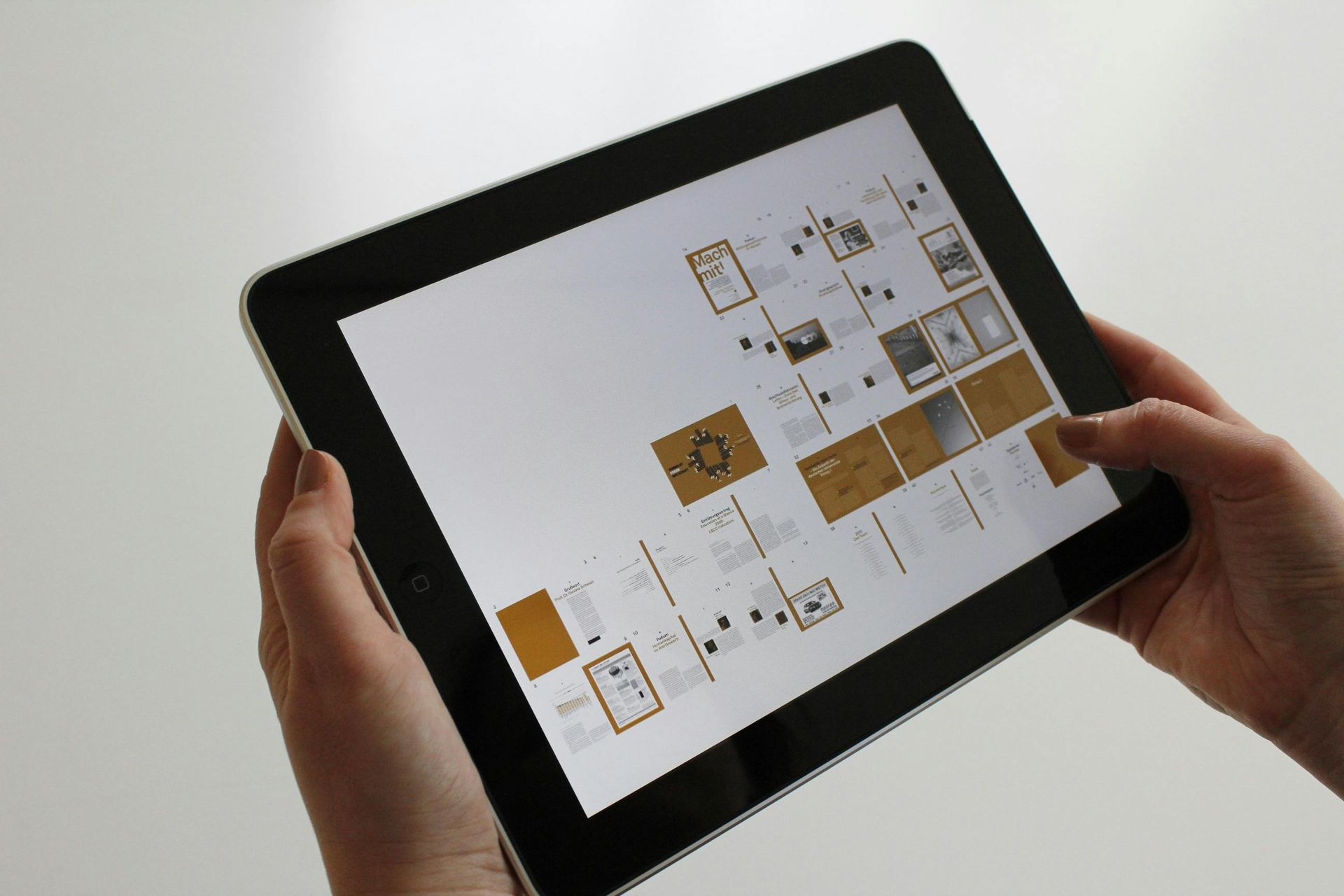 Hands holding a tablet displaying a digital document with images and text.