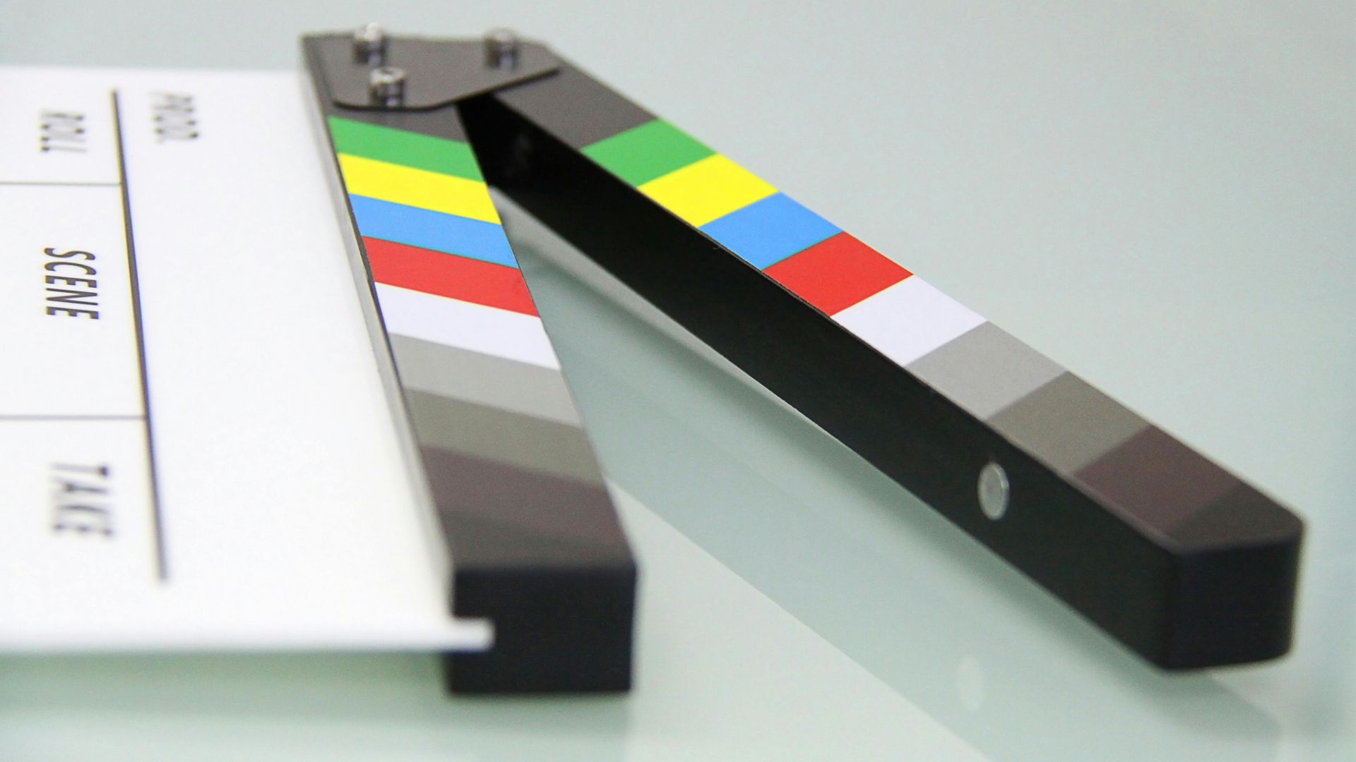 Clapperboard open, showing a white card with text and a colorful, grayscale color bar.