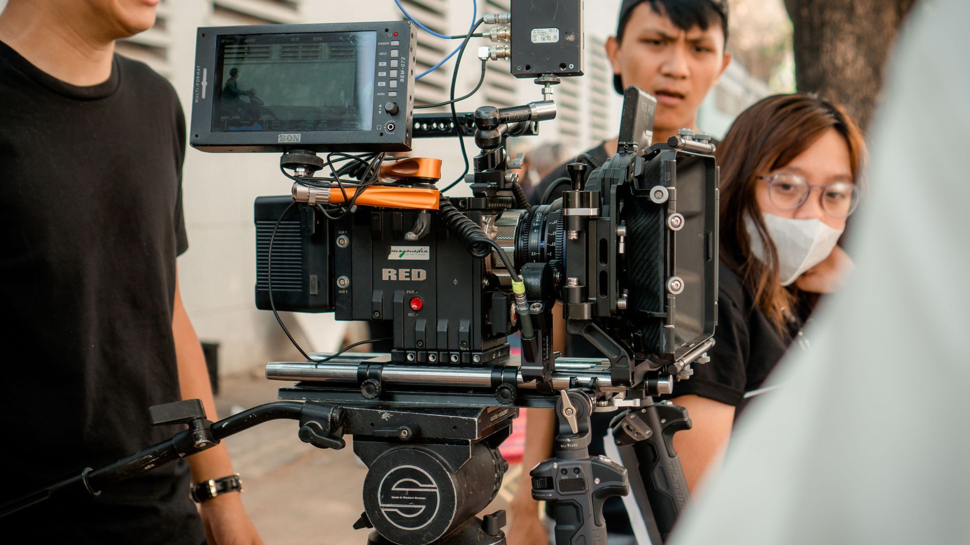 Film crew operating a professional camera rig outdoors, with crew members around the monitor.
