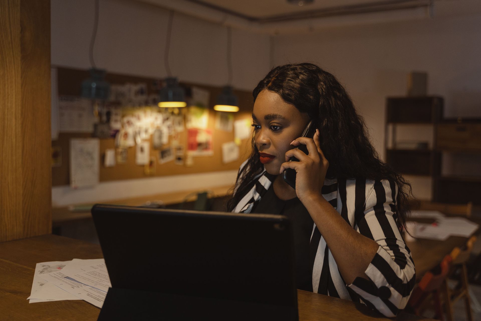 Person on a phone call behind a laptop in a softly lit office workspace