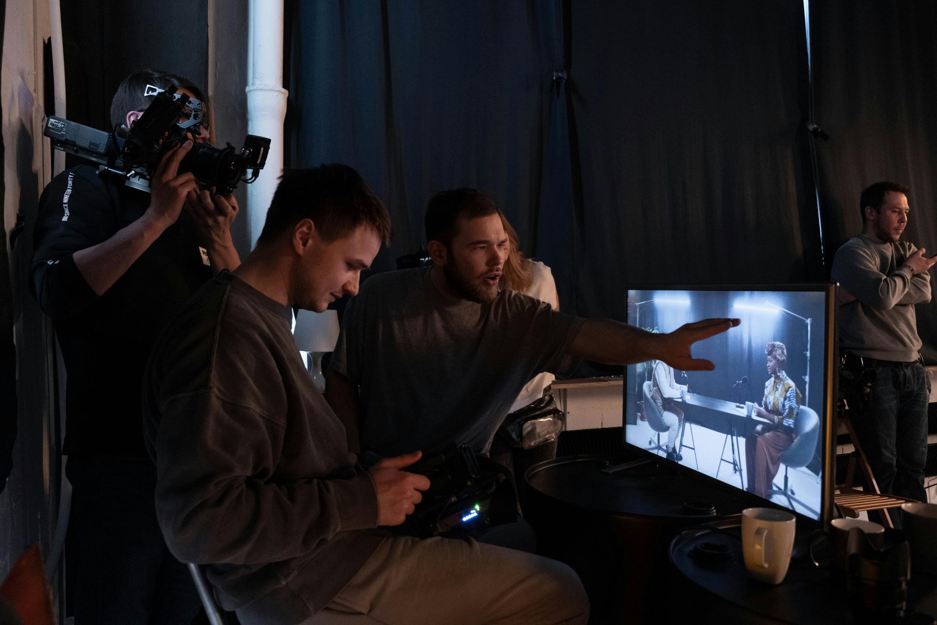 A group of men are sitting in front of a computer screen.