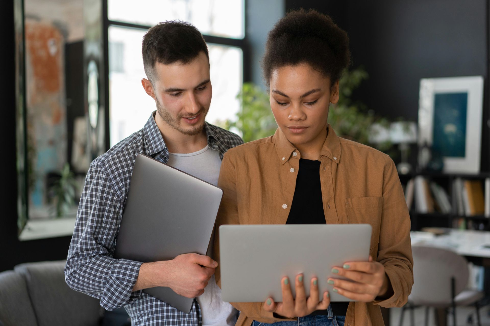 Two people looking at a laptop together in a brightly lit office setting.