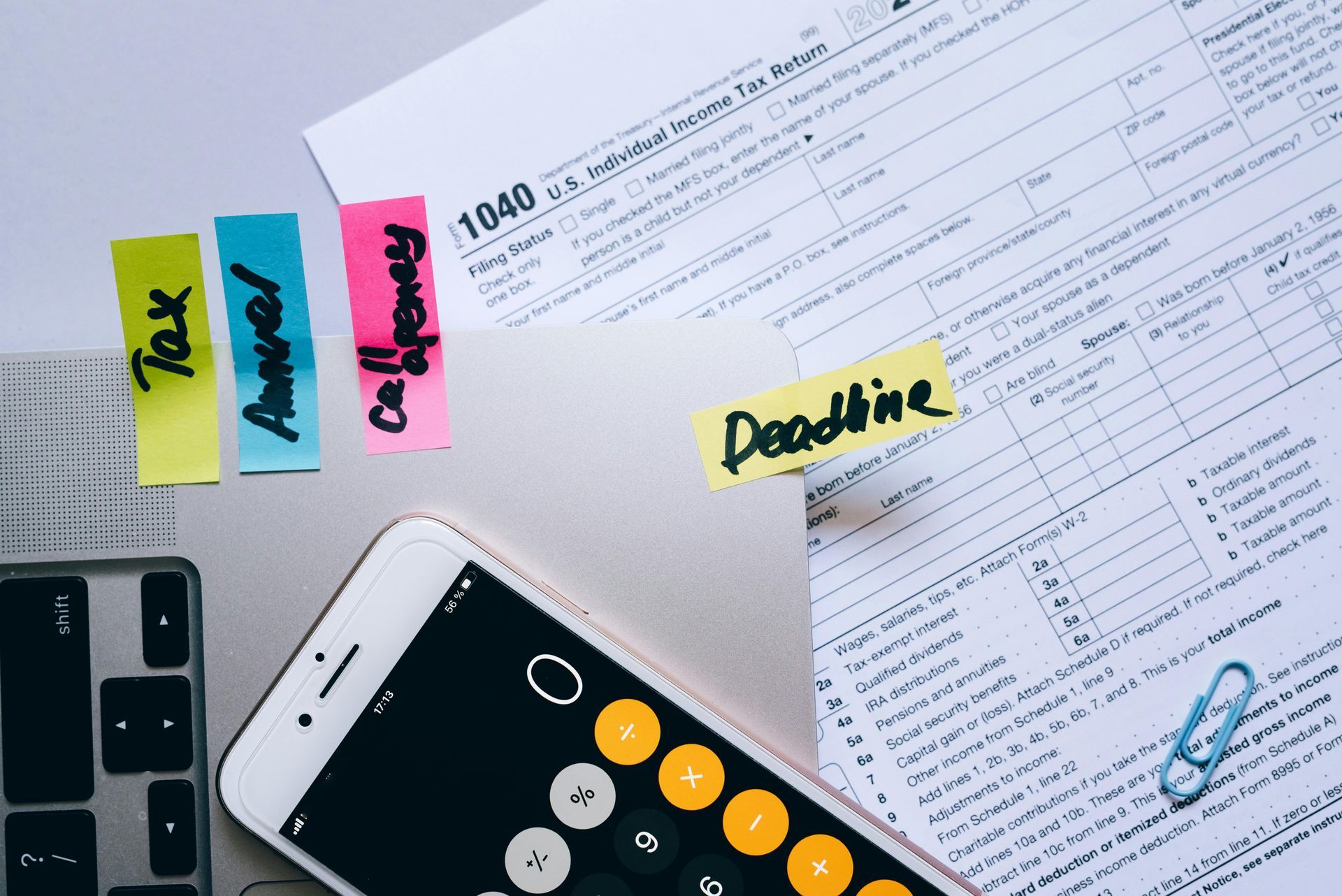 Tax forms with sticky notes and a calculator, highlighting tax deadline.