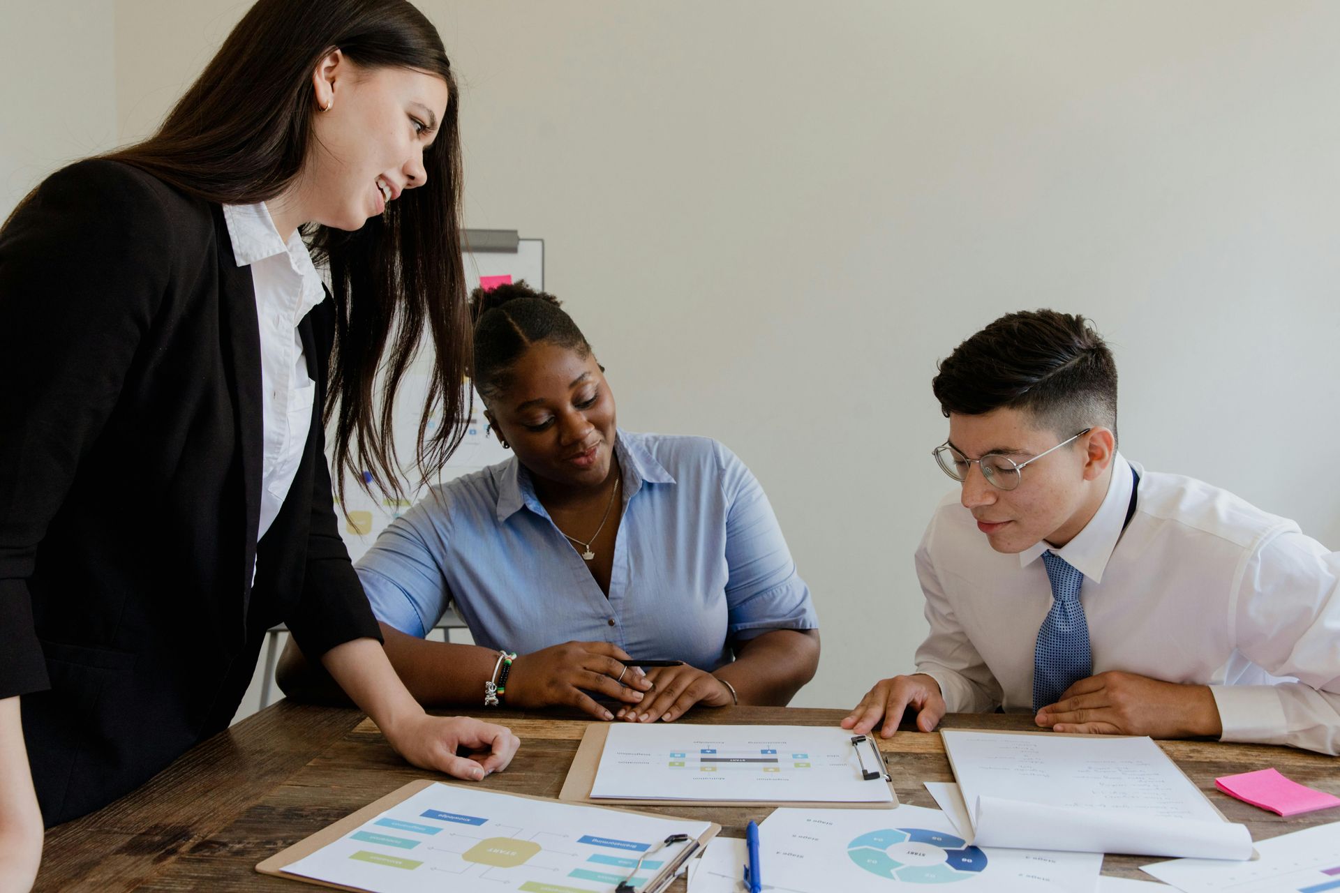 Three business colleagues, two women and a man, reviewing paperwork at a table in an office.