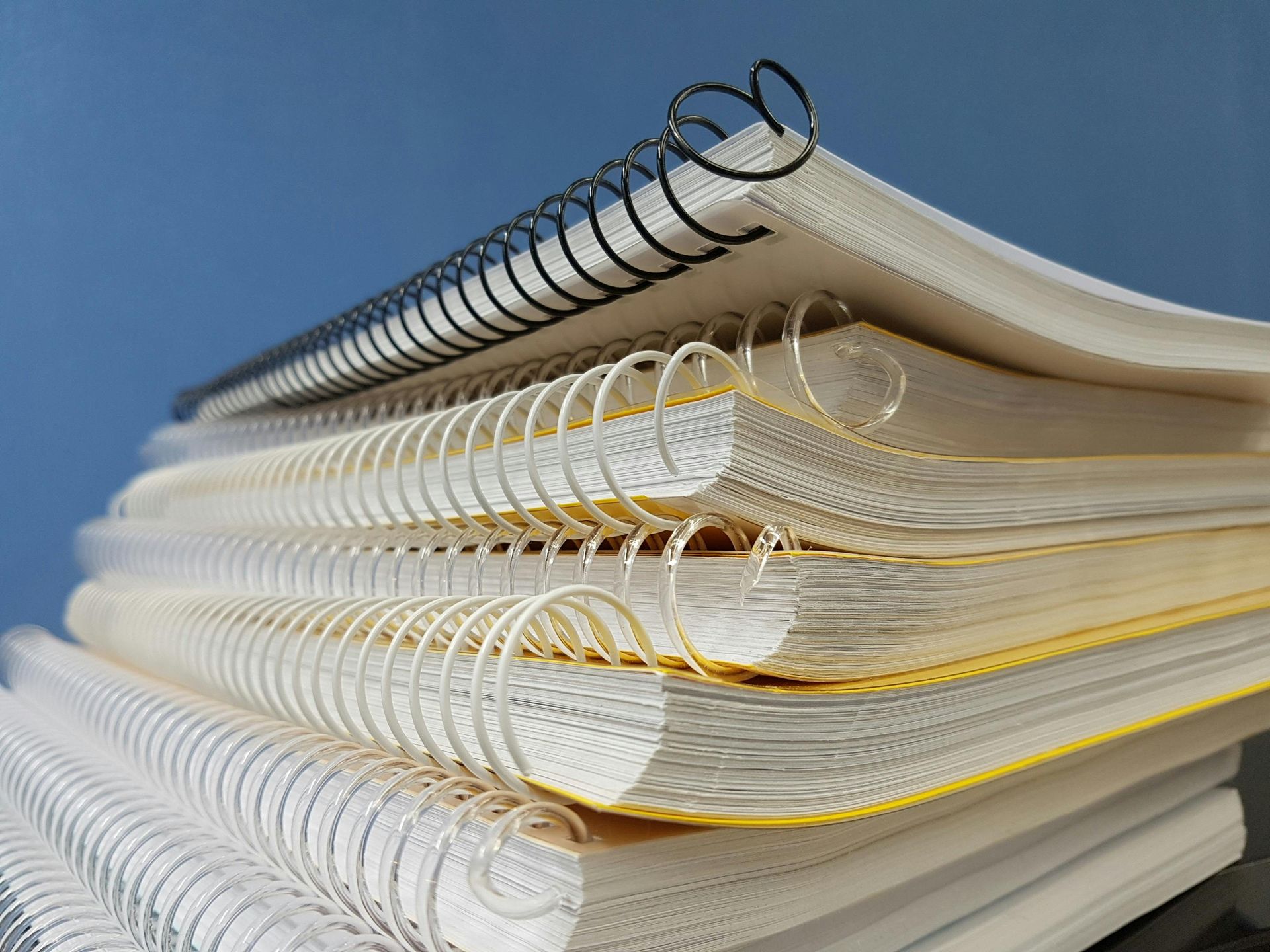 A stack of spiral notebooks with a blue background