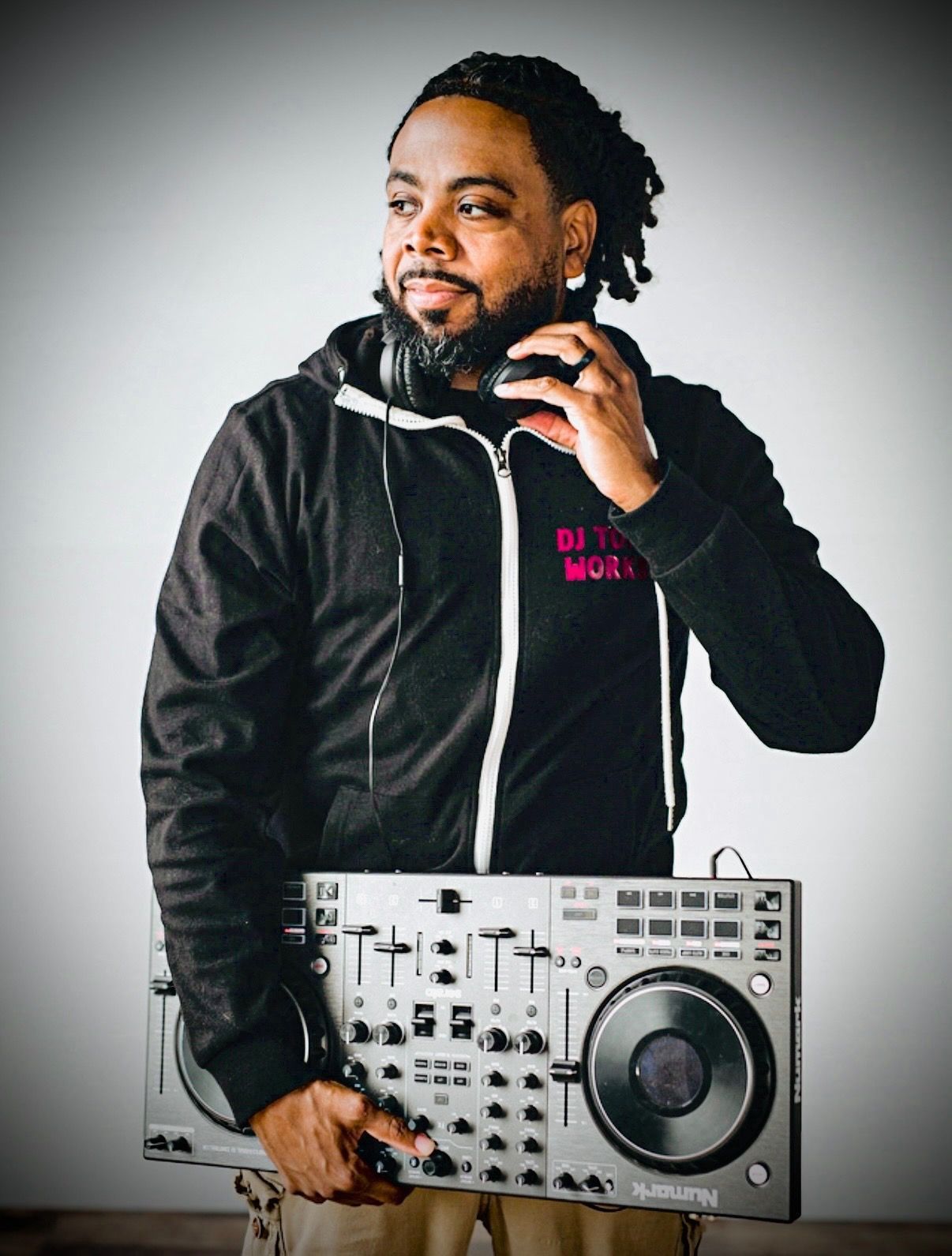 Man holding DJ mixer, wearing headphones and jacket with