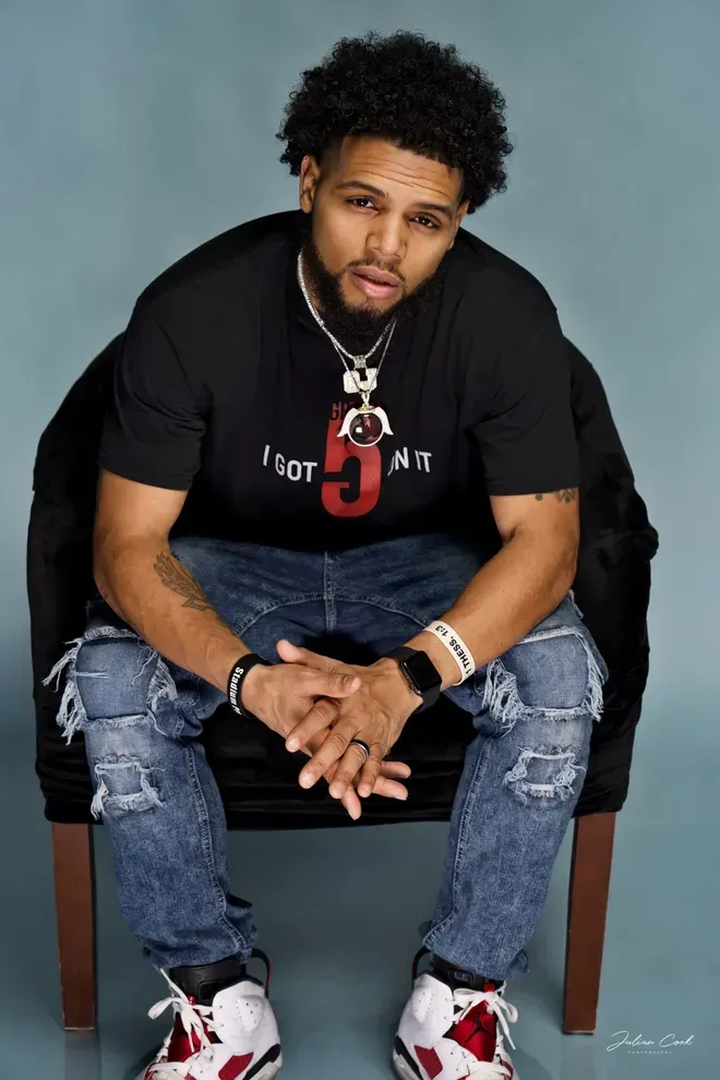 Man seated, wearing black t-shirt with a red
