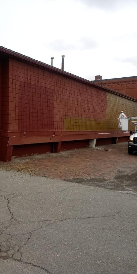 Red brick building with a loading dock, on a cracked asphalt surface.