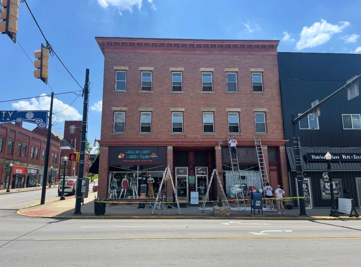 Brick building on a city street; storefronts at ground level, several stories above, blue sky.