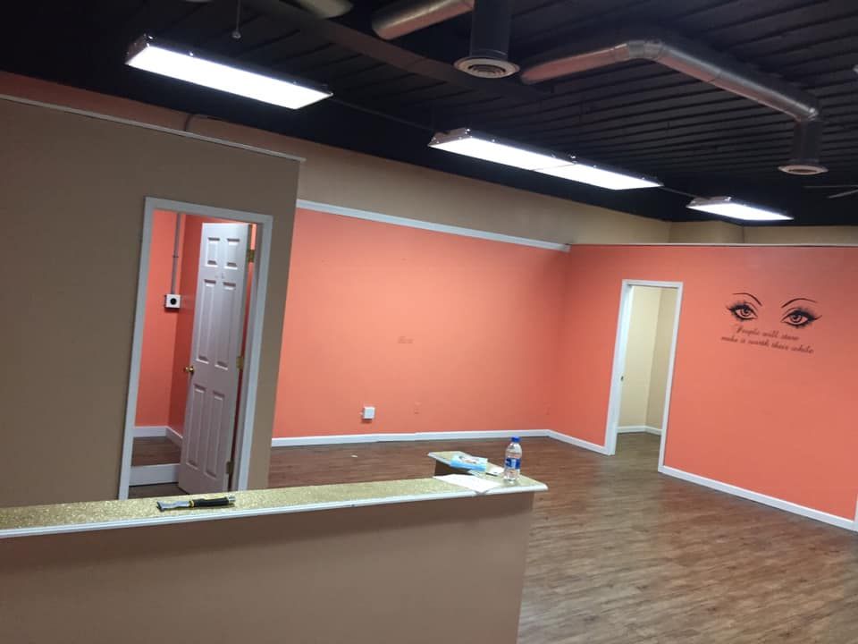 Empty room with peach walls, white trim, wood floor, and black ceiling.