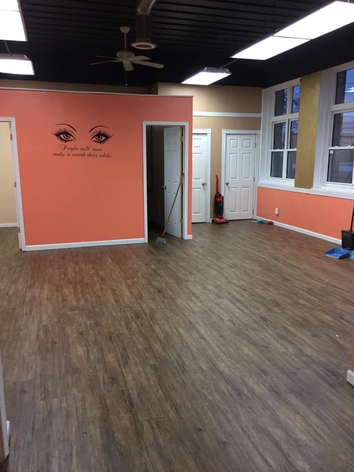 Empty room with wood-look flooring, peach and beige walls, black ceiling, and white doors and windows.