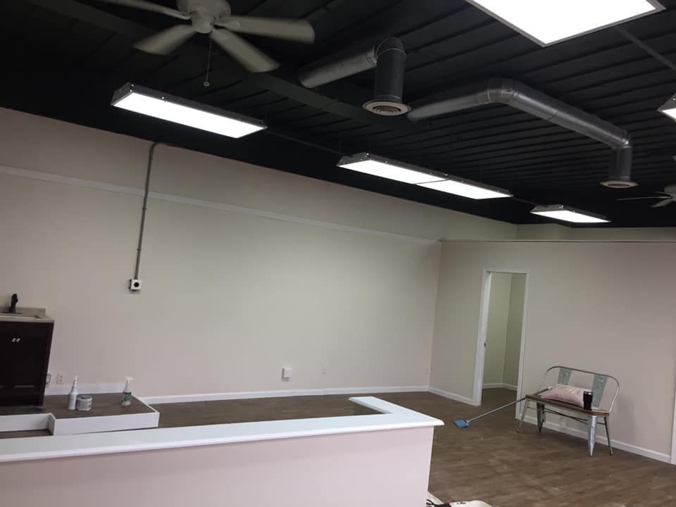 Empty interior with white walls, black ceiling with lights and fans, and a bar.