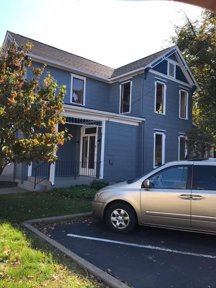 Blue two-story house with white trim. A tan minivan is parked in front.