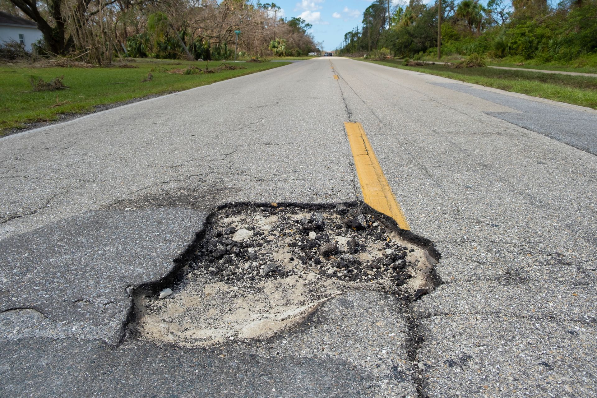 A pothole in the middle of a road with a yellow line.