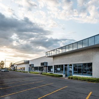 A large building with a lot of windows and a parking lot in front of it.