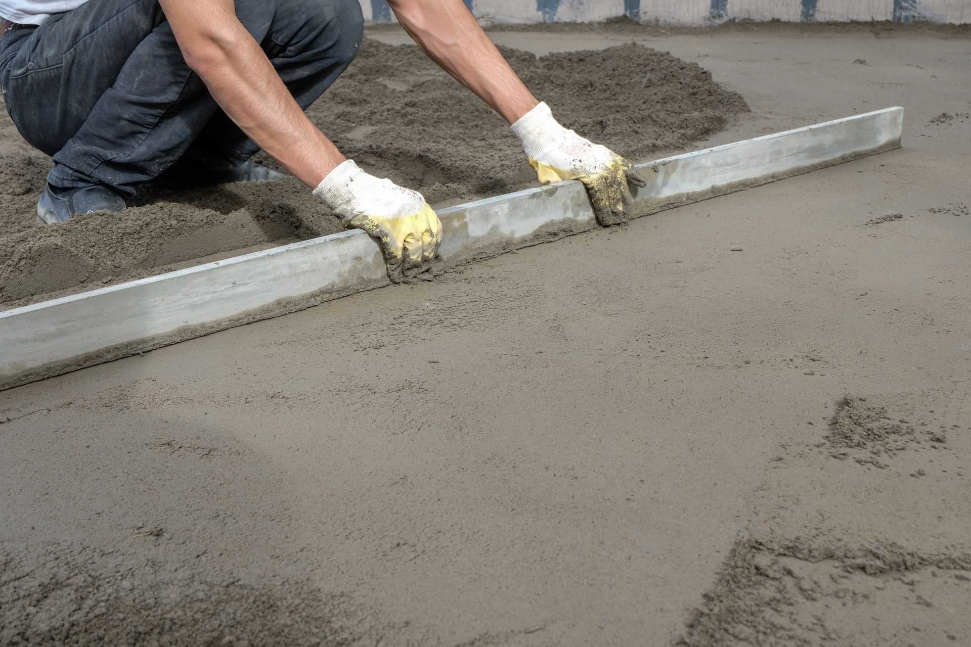 A man is leveling a concrete floor with a level.
