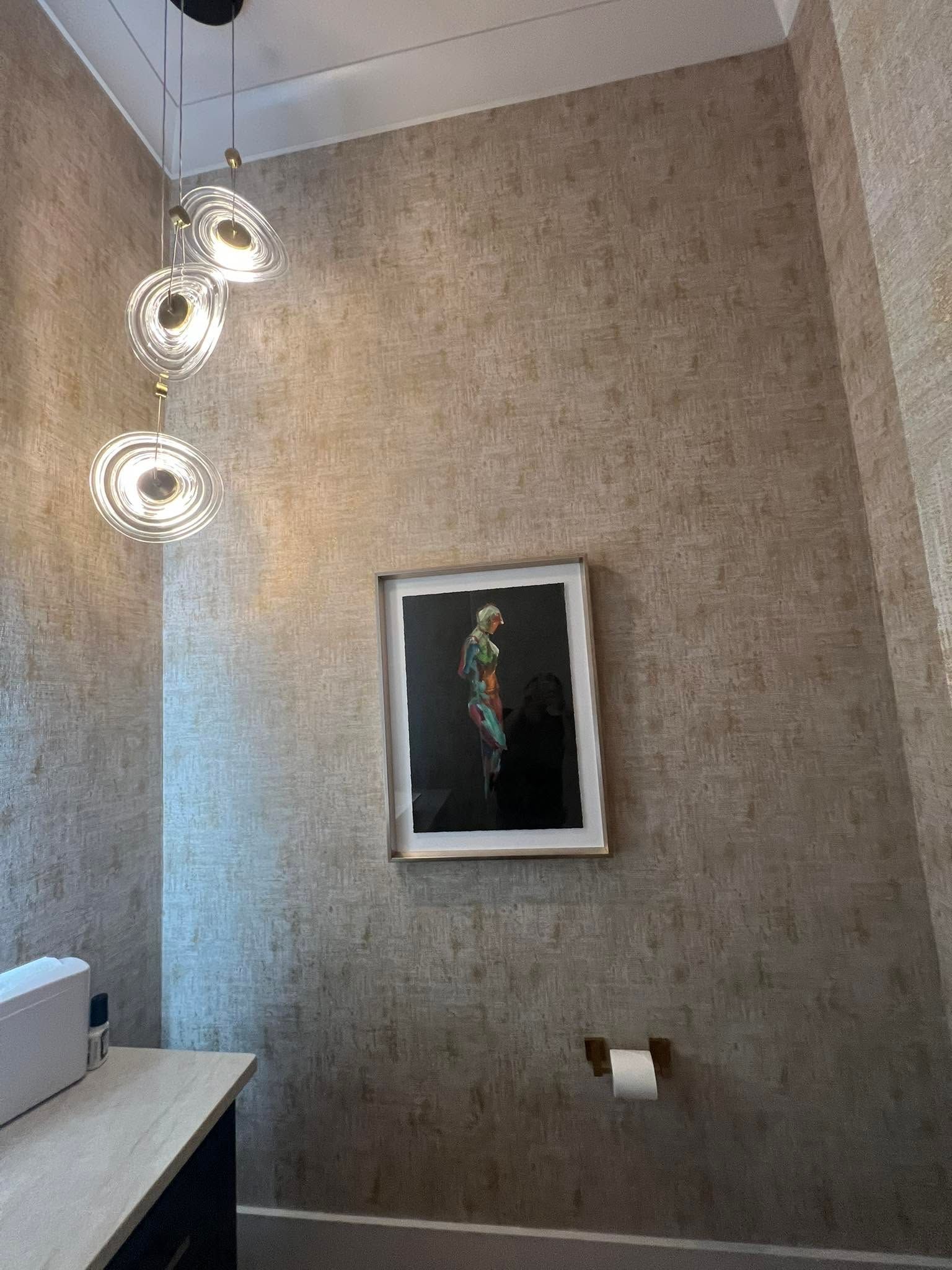 Modern bathroom wall with framed artwork and three hanging pendant lights