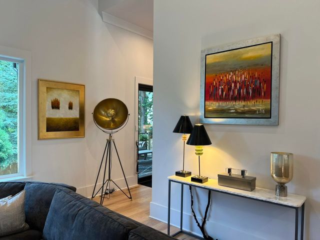 Modern living room with blue couch, floor lamp, console table, and colorful artwork on white walls