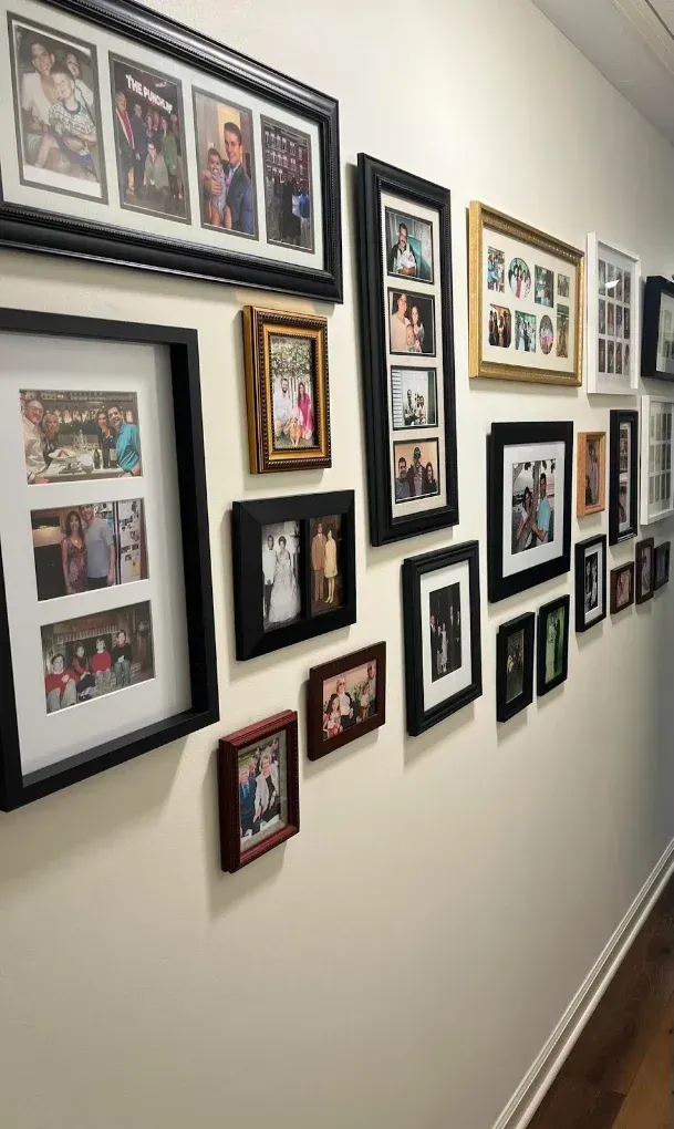 Hallway wall covered with a gallery of framed family photos and collages.