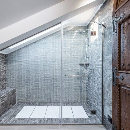 A bathroom with a walk in shower and a wooden door.
