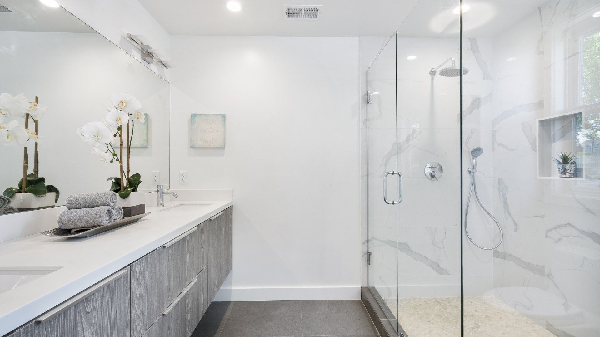 A bathroom with a walk in shower , sink and mirror.