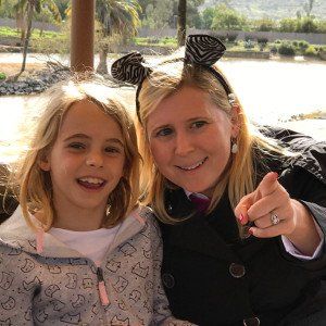 A woman and a little girl are posing for a picture and the woman is pointing at the camera.
