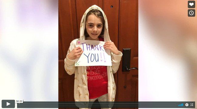 A young girl is holding a thank you sign.