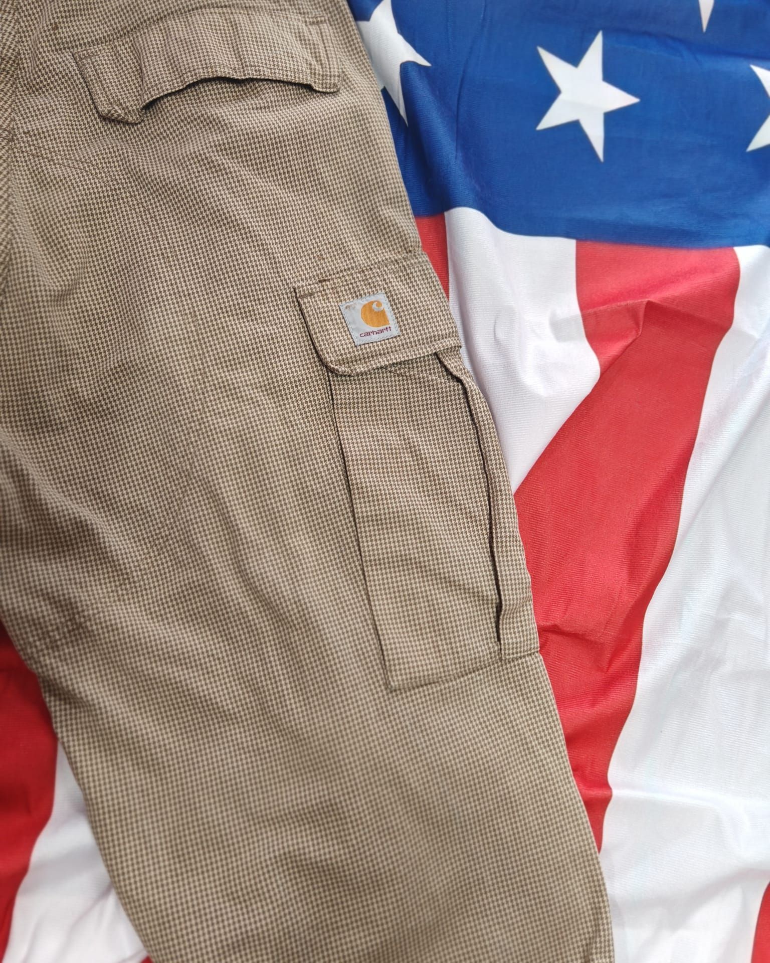 Pantaloni cargo color kaki con tasca su uno sfondo con la bandiera americana rossa, bianca e blu.