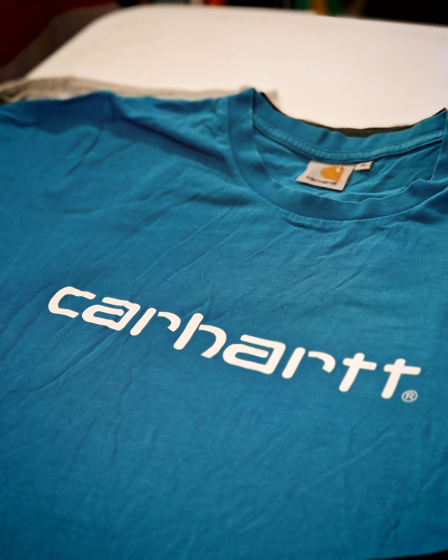 T-shirt blu Carhartt con logo bianco stesa su una superficie